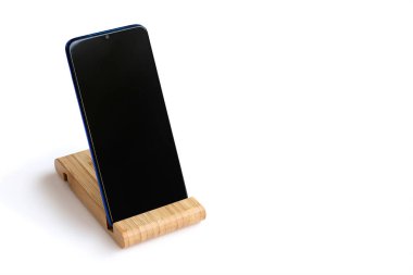 Akıllı telefon beyaz izole bir arka planda ahşap bir standın üzerinde duruyor. Tahta akıllı telefon standı. Boşluğu kopyala.