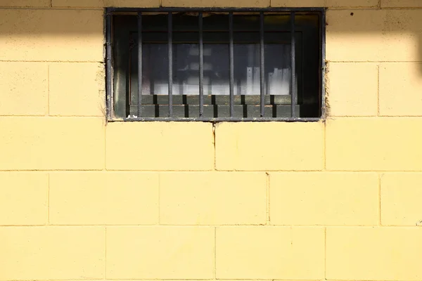 Yellow brick wall texture with window and prison cell bars — Stock Photo, Image