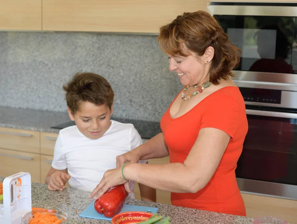 Ευτυχισμένη μητέρα και γιος που ετοιμάζουν μεσημεριανό. Κοπή κόκκινο πιπέρι — Φωτογραφία Αρχείου