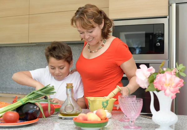 Η μητέρα και ο γιος ετοιμάζουν μεσημεριανό και χαμόγελα. Κοπή κόκκινο πιπέρι — Φωτογραφία Αρχείου