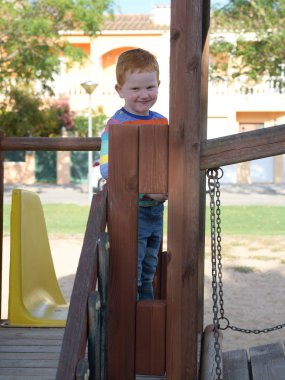 5 yaşındaki kızıl saçlı mutlu çocuk oyun alanında gülümsüyor