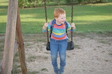 Sırt çantası sallanan ve gülümseyen 5 yaşındaki kızıl saçlı mutlu çocuk