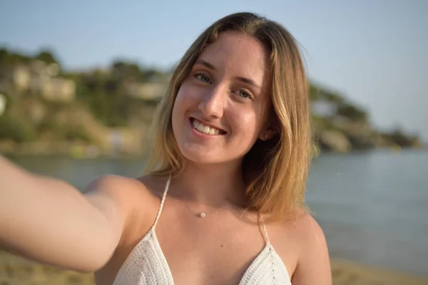 De cerca retrato de una chica sonriendo y tomando selfie en la playa — Foto de Stock