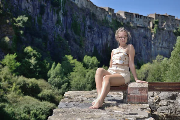 Mladá dívka, která sedí se středověkou vesnicí v pozadí na útesu — Stock fotografie