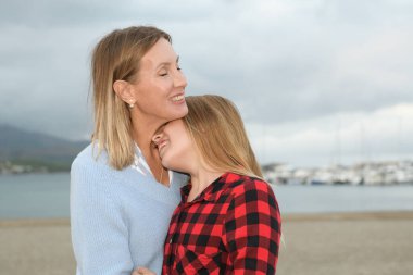 Anne ve kızı sarıldı ve mutlu oldu. Sevgisini deniz kenarında gösterdi.