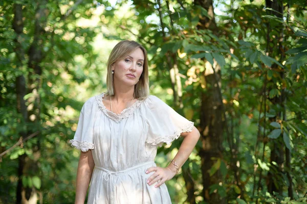 Mujer parada en un bosque y mirando a la cámara — Foto de Stock