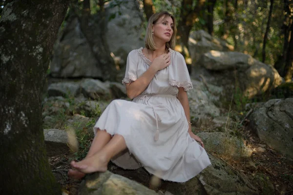 Mujer en un bosque sentada y relajada mientras el sol se pone — Foto de Stock