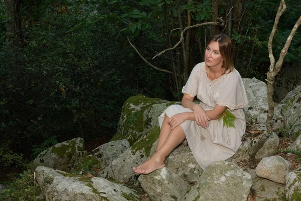 해 가 지면서 숲 속에 앉아서 쉬고 있는 여성 — 스톡 사진