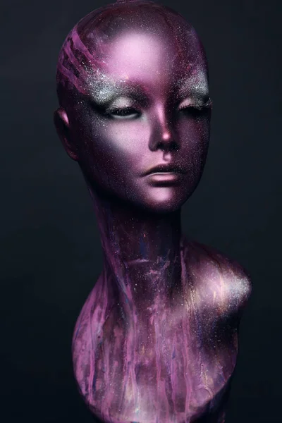 Closeup studio shot of violet woman mannequin with stylish makeup, dark background