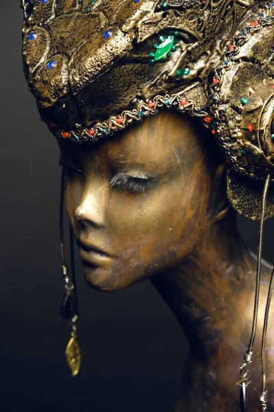 Bronze head of mannequin in decorated bronze kokoshnick, dark studio background