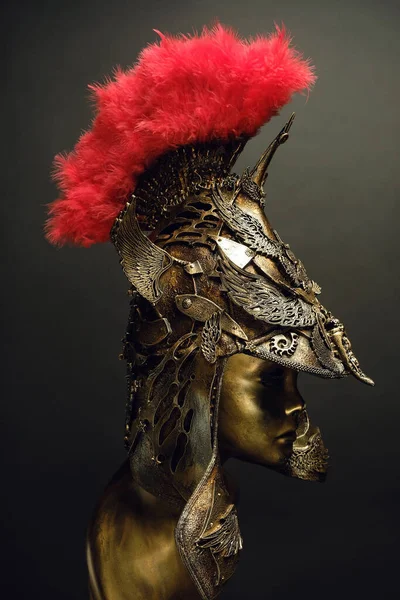 Mannequin in helmet with feathers on dark background