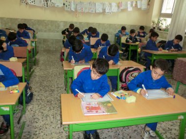  Elementary school boys  Gilan Iran. One of the primary school boys in Rasht, Guilan province, Iran.  Students are wearing school uniforms. Students are busy writing on paper. clipart