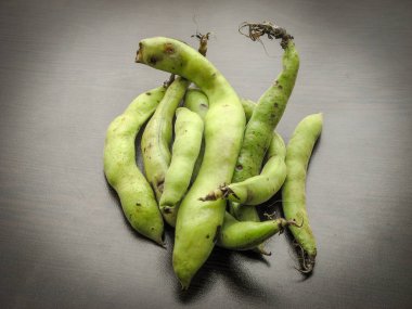 Siyah ahşap masa üzerinde pod taze aldı ham geniş fasulye closeup. Siyah artalan üzerinde izole geniş fasulye Kapsüller