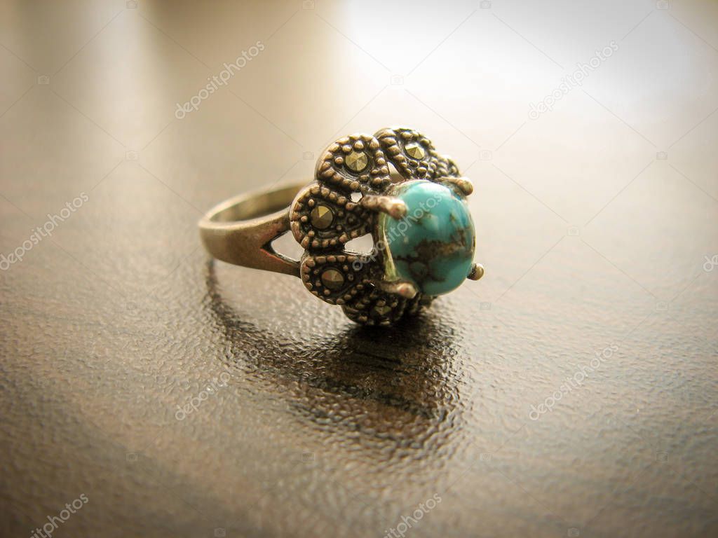 Blue turquoise ring Women's ring. Closeup of silver ring decorated with blue turquoise stone. Muslims use it as a holy stone.Turquoise ring on dark wooden background.