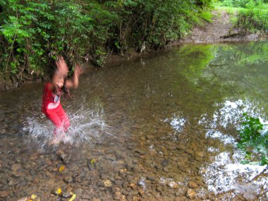 Nehirde oynayan tatlı küçük kız. Ormanda nehirde Asyalı bir kız.