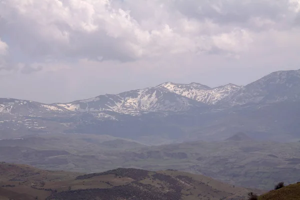 View over the hill with mountain trail and snowy mountains on the background. Beautiful mountain trail landscape. Morning  Alborz mountain trail scenery in Iran, Gilan