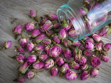 Ahşap arka planda cam şişedeki çay için kuru gül tomurcukları. Antioksidan ve sağlıklı gül tomurcukları. Kapatın. Geleneksel tıpta mutluluk. Aromaterapi