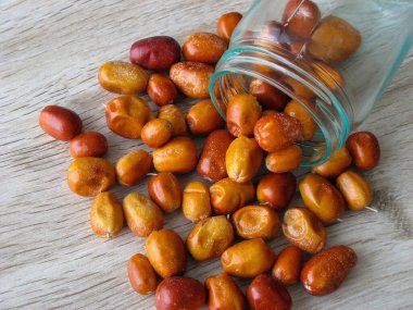 Oleaster 'ın organik kurutulmuş meyvesi ahşap masadaki cam bir şişeye saçılmış. Oleaster, Silver berry, Pers zeytini veya yakın mesafeden yabani zeytin veya Rus zeytininin taze meyvesi. Arkaplan. 