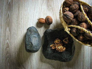 Olgun organik cevizler ahşap masadaki taşın üzerinde kırılan cevizlerin yanındaki hasır sepetin içinde. Kapatın. Üst Manzara. Sağlıklı yaşam tarzı.