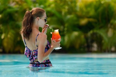 Yüzme havuzunda bir kokteylle genç kadın