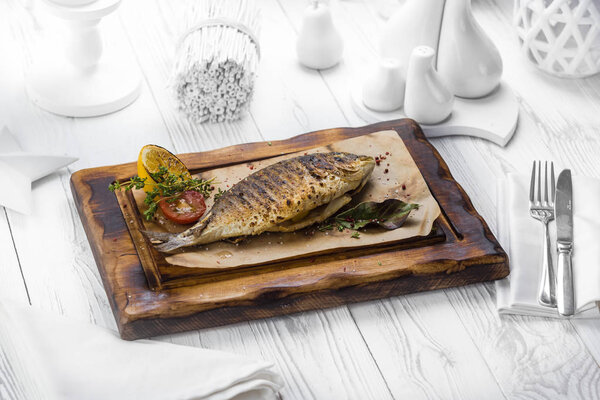 Tasty grilled fish with lemon on a board