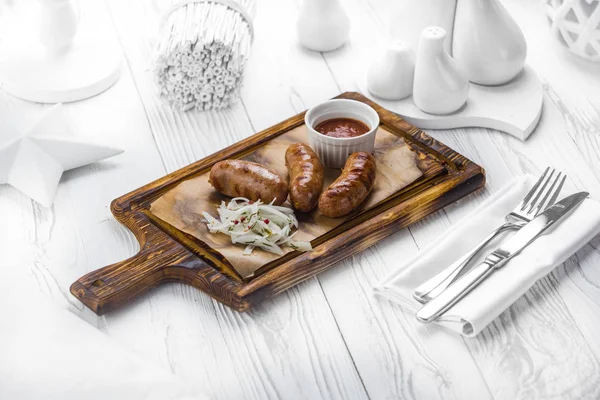 Würstchen mit Zwiebeln und Tomaten-Dip-Sauce auf einem Brett — Stockfoto