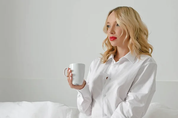 Blondes Mädchen trinkt morgens Kaffee im Bett. — Stockfoto