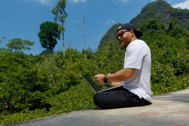 Young stylish bearded blogger working on vacation in the mountains.