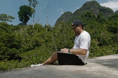 Young stylish bearded blogger working on vacation in the mountains.