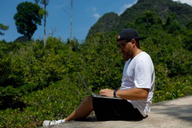 Young stylish bearded blogger working on vacation in the mountains.