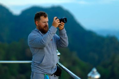 Genç bir adam seyahat ederken fotoğraf çeker.