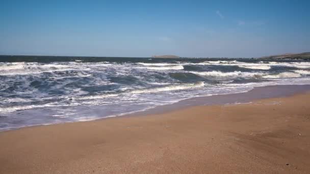 Large storm surges on a deserted sandy beach against the backdrop of small mountains on a Sunny summer day. — Stock Footage Large storm surges on a deserted sandy beach against the backdrop of small mountains on a Sunny summer day. Royalty Free Stock Footage