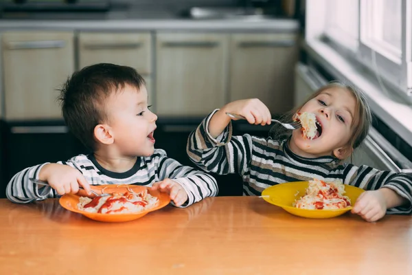 Boy and girl in the kitchen eating pasta