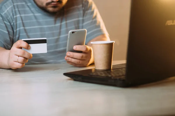 Cropped picture of man with credit card white pattern and phone