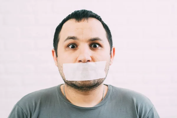 Angry man mouth covered by masking tape