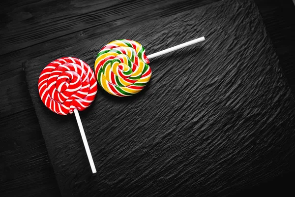 red and yellow round lollipops on black background with texture