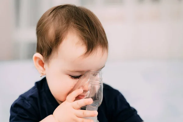 a little girl yourself holding the mask of the nebulizer, making inhalation