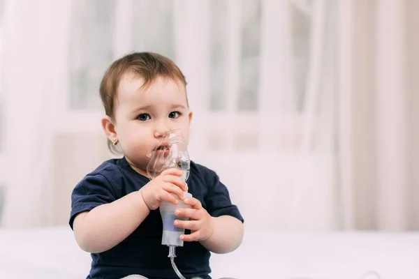 a little girl yourself holding the mask of the nebulizer, making inhalation