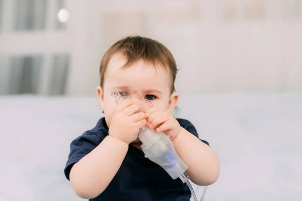 a little girl yourself holding the mask of the nebulizer, making inhalation