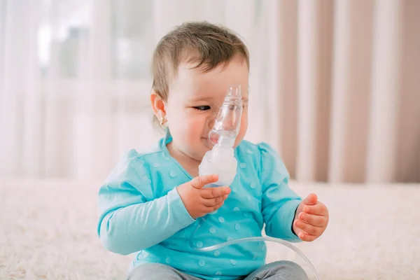 a little girl yourself holding the mask of the nebulizer, making inhalation