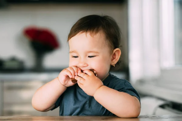 little girl in the afternoon in the kitchen eating a delicious chocolate bar