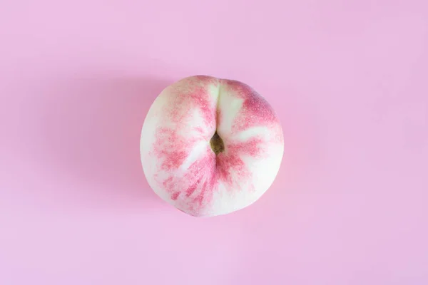 flat peach isolated on pink background. one figs, the peach, is located in the centre. fresh delicious peach