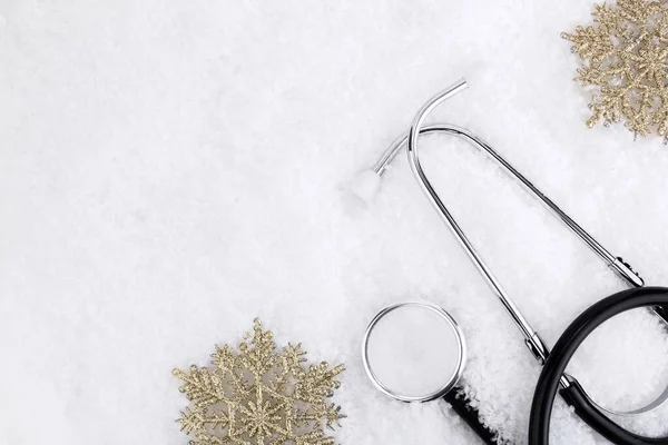 Medical stethoscope on a snowy background near snowflakes. Medical concept for Christmas or New Year. Flatly. Copy space