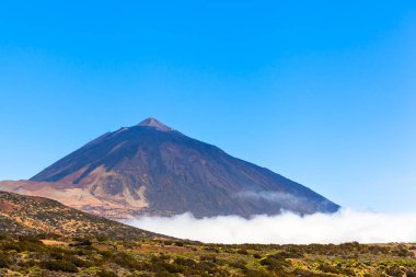 Tenerife adasındaki milli parktaki bulutların üstündeki Teide dağına bak, mavi gökyüzü boşluğu kopyala