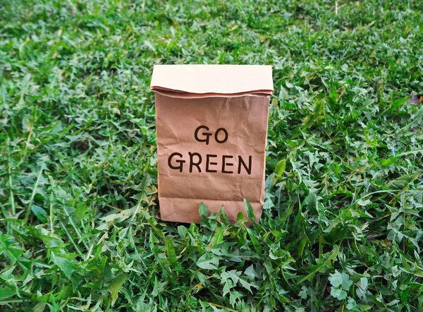 Go green ecological shopping bag on the green grass. An alternative to disposable packages. Zero waste concept.