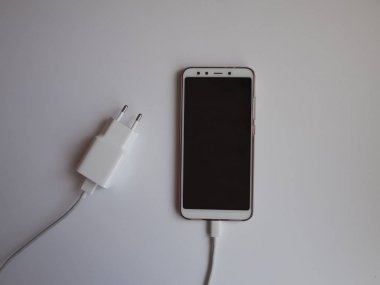 Üst görünümü şarj etmek için beyaz Usb kablosuna sahip bir akıllı telefon