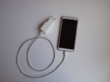 Üst görünümü şarj etmek için beyaz Usb kablosuna sahip bir akıllı telefon