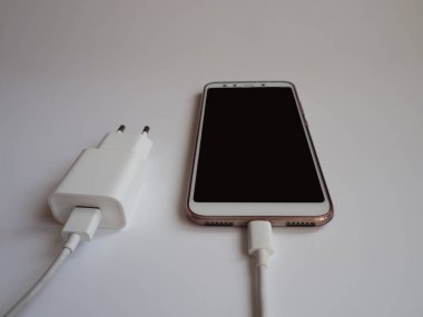 Şarj etmek için beyaz kablolu bir cep telefonu