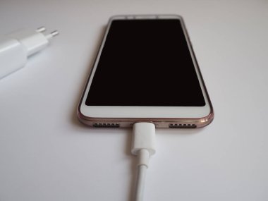 Yakın görünümü şarj etmek için beyaz Usb kablosuna sahip bir akıllı telefon
