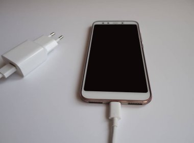 Şarj etmek için beyaz Usb kablosuna sahip bir akıllı telefon